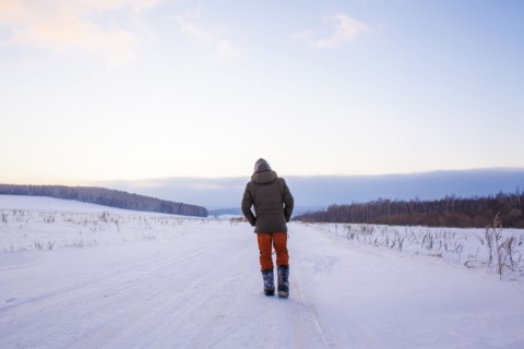 Mixed race man walking in snowy field