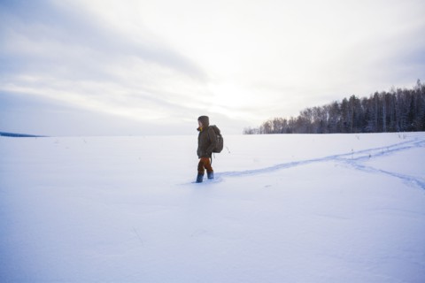 Mixed race man walking in snowy field