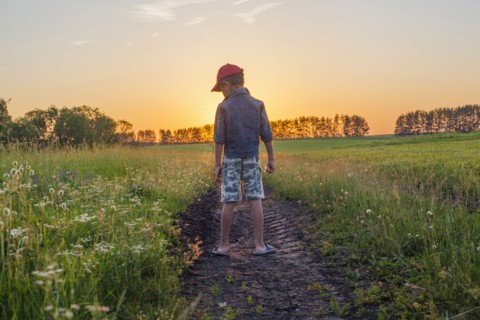 Mari boy standing in tire tracks in rural field