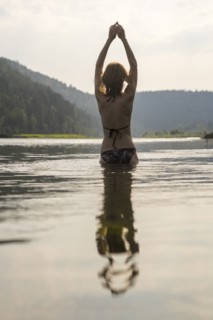 Caucasian woman standing in lake wearing bikini