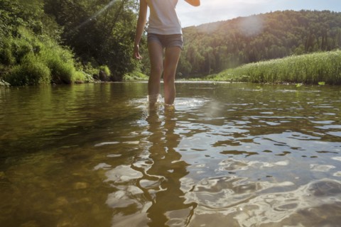Caucasian woman wading in river