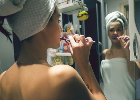 Caucasian woman brushing teeth in mirror