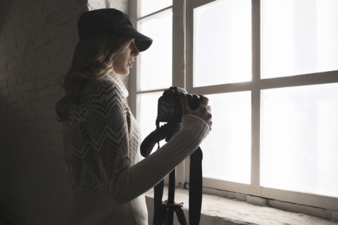 Caucasian woman near window holding camera