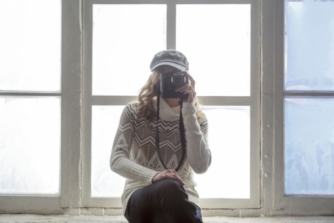 Caucasian woman on window sill photographing with camera