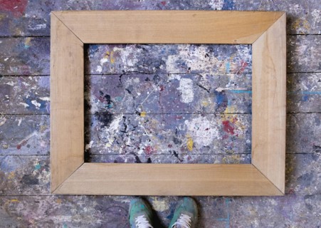 Feet standing over picture frame on wooden floor