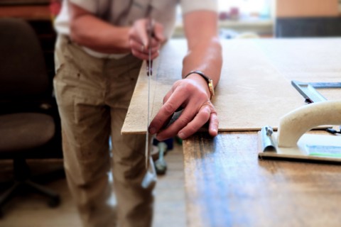 Midsection of Caucasian man cutting panel with saw