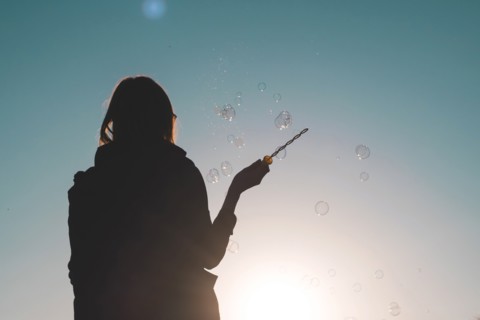 Silhouette of a woman waving bubble wand