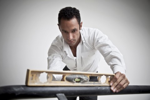 Hispanic man using level on railing