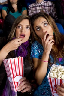 Hispanic friends enjoying popcorn in movie theater