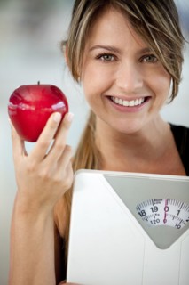 Hispanic woman holding apple and weighting scale