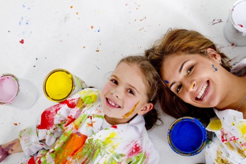 Hispanic mother and daughter covered in paint laying on floor