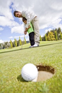 Hispanic man teaching boy to play golf