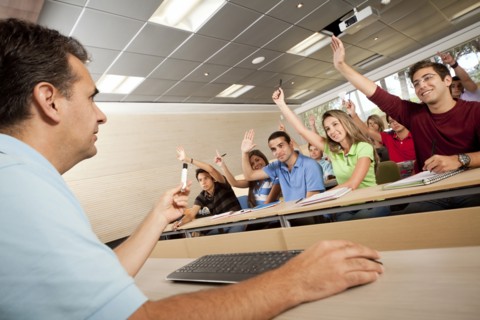 Hispanic college students raising arms in classroom