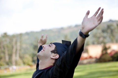 Hispanic college graduate cheering with arms raised