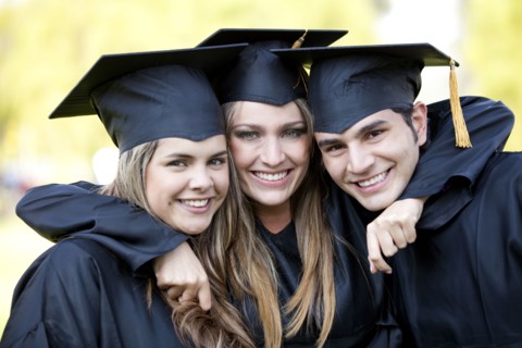 Hispanic graduates in caps and gowns hugging
