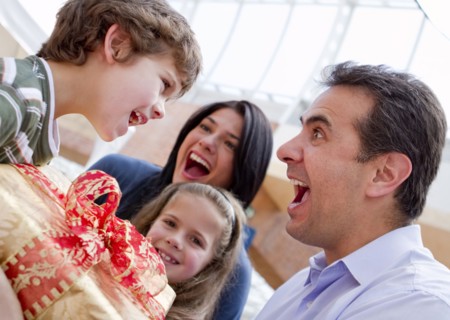Hispanic father giving excited son birthday gift