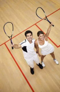 Hispanic couple raising squash racquets