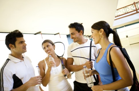 Hispanic couples on squash court drinking water