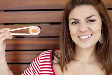Hispanic woman smiling with sushi