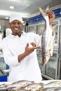 Mixed race grocer preparing fish in market