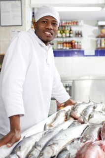 Mixed race grocer preparing fish in market