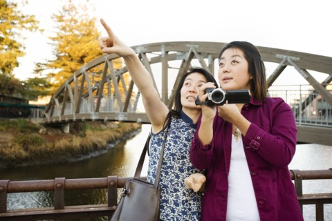 Chinese mother and daughter taking photographs outdoors