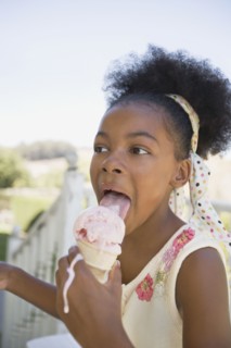 Mixed race girl licking melting ice cream cone