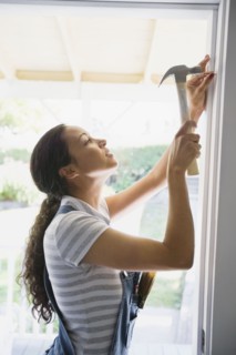 Mixed race woman hammering nail in doorway
