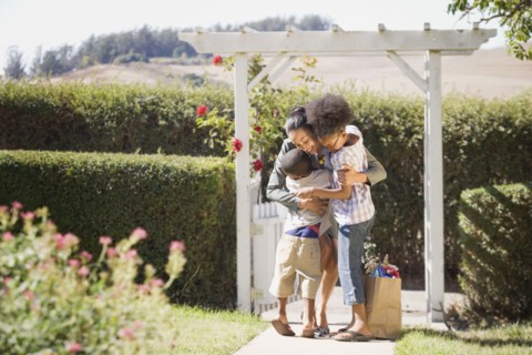 Mother with groceries hugging children