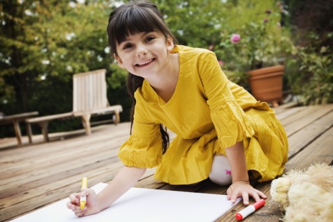 Mixed race girl coloring on deck