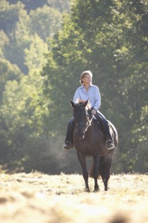 Caucasian woman riding horse in field