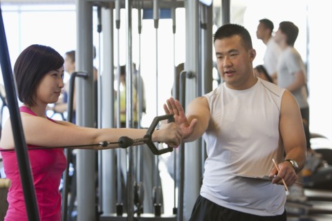 Woman working with personal trainer in health club