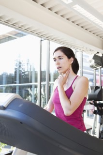 Woman on treadmill checking her pulse