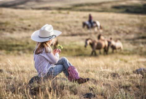 Caucasian girl sitting on rock in field holding flower
