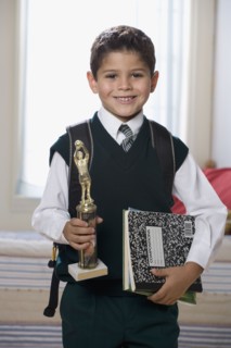Hispanic boy holding trophy and school books