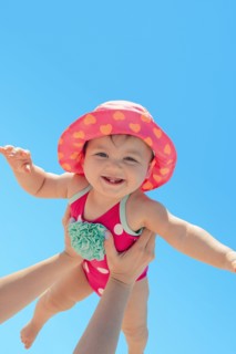 Woman holding baby girl against blue sky