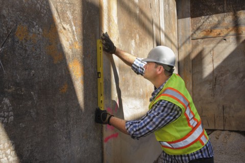 Caucasian construction worker holding level against wall