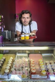Hispanic business owner showing cupcakes bakery display case