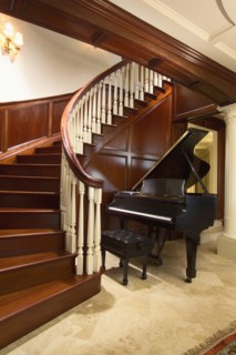 Baby grand piano at foot of large winding staircase