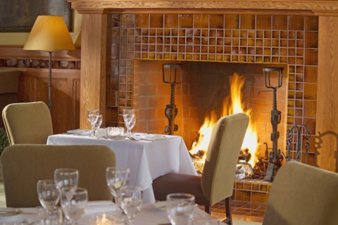 Simple dining table in front of warm fireplace