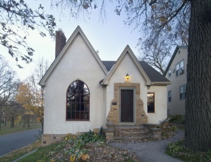 Front exterior view of white cottage with stone stairs and pointed rooftops