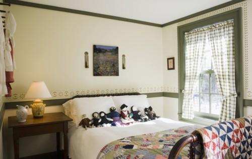 Small colonial bedroom with collection of amish dolls on bed