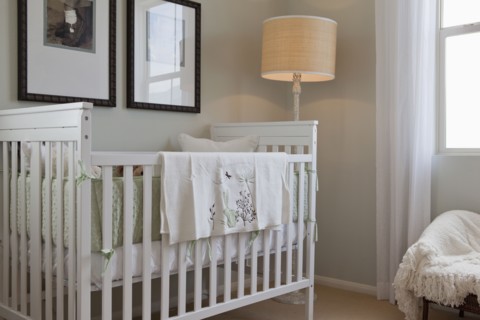 Baby's crib with floor lamp and picture frames in the house