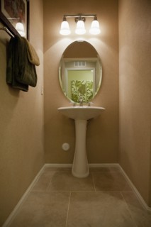 Oval mirror with wall lamps at pedestal washbasin at home