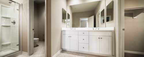 Bathroom with cropped commode and washbasin with cabinets at mirror