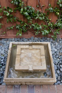 Square shaped fountain and pebbles outside house