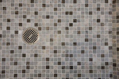 Close-up of drain in mosaic tile floor in the bathroom at home