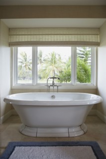 Modern bathtub with detachable shower head in front of window