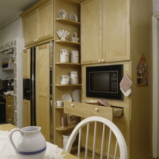 View of microwave with wooden cabinets and refrigerator