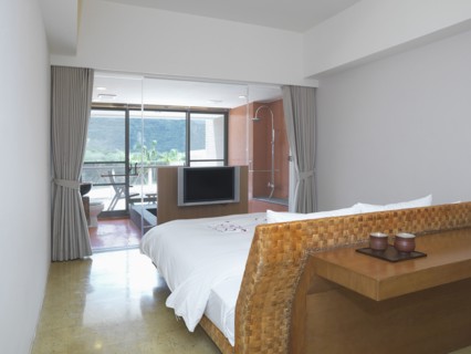Small modern bedroom with glass wall separating from bathroom